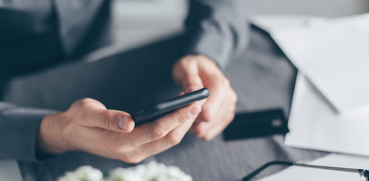 Seorang pria urban sedang melihat layar ponsel pintar yang menampilkan aplikasi transaksi pembayaran digital