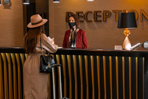 Ilustrasi seorang petugas hotel ramah melayani pemesanan langsung pelanggannya yang akan menginap. 
