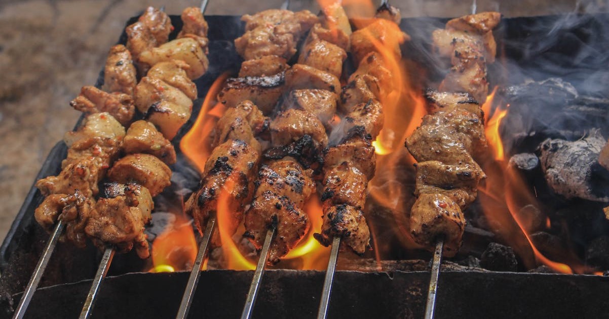  Olah Daging Kambing: Sajian hidangan sate daging kambing bumbu kecap tradisional yang menggugah selera yang sedang dibakar.