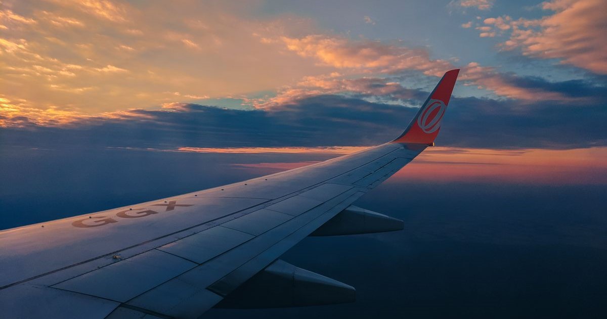 Berburu tiket pesawat murah: Ilustrasi pesawat terbang di langit cerah di atas awan