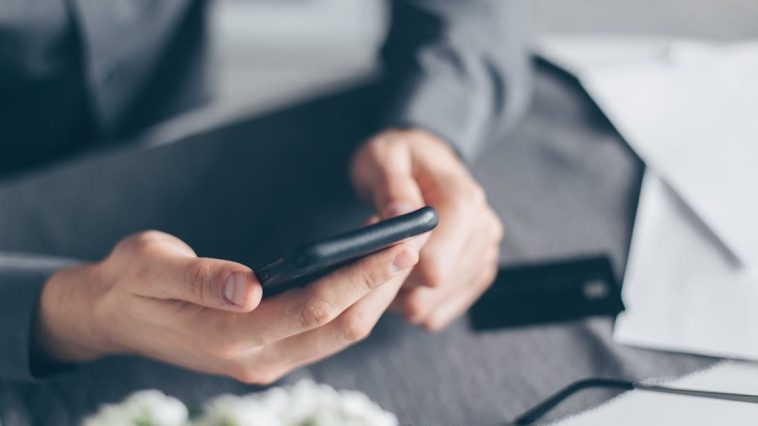 Aplikasi Kurban Digital 2026: Seorang pria urban sedang melihat layar ponsel pintar