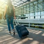 Seorang traveler membawa koper di bandara sebagai ilustrasi cara atasi jet lag.