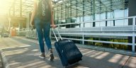 Seorang traveler membawa koper di bandara sebagai ilustrasi cara atasi jet lag.
