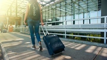 Seorang traveler membawa koper di bandara sebagai ilustrasi cara atasi jet lag.