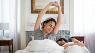 Gerakan peregangan tangan di atas kasur saat bangun tidur di pagi hari yang cerah