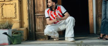 OOTD jersey bola: Seorang pria muda tampil modis mengenakan jersey vintage yang dipadukan dengan celana jeans longgar dan sepatu kets retro