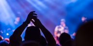 Panduan konser musik 2026: Ilustrasi suasana panggung konser musik besar di malam hari dengan gemerlap lampu sorot dramatis dan lautan penonton