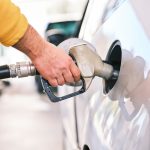 Seseorang sedang memegang nozzle dispenser bensin di SPBU perkotaan modern, Tips hemat bensin mobil ini bisa diterapkan dengan mudah.