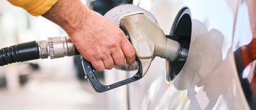 Seseorang sedang memegang nozzle dispenser bensin di SPBU perkotaan modern, Tips hemat bensin mobil ini bisa diterapkan dengan mudah.