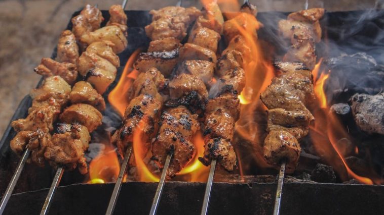 Olah Daging Kambing: Sajian hidangan sate daging kambing bumbu kecap tradisional yang menggugah selera yang sedang dibakar.