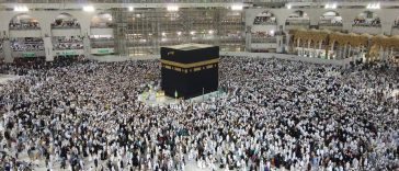 Alt Text: Waspada Visa Non-Haji: Ilustrasi lautan jemaah haji berpakaian ihram putih sedang berjalan khusyuk mengelilingi Ka'bah saat prosesi tawaf di Masjidil Haram Makkah