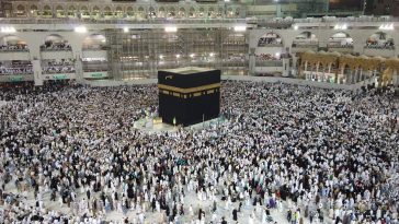 Alt Text: Waspada Visa Non-Haji: Ilustrasi lautan jemaah haji berpakaian ihram putih sedang berjalan khusyuk mengelilingi Ka'bah saat prosesi tawaf di Masjidil Haram Makkah