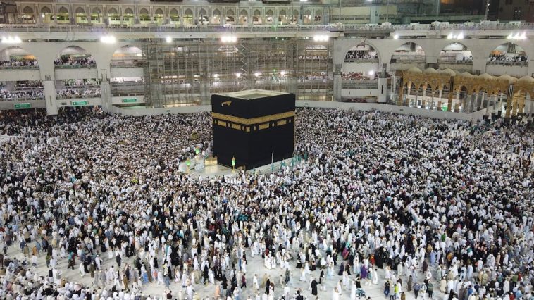 Alt Text: Waspada Visa Non-Haji: Ilustrasi lautan jemaah haji berpakaian ihram putih sedang berjalan khusyuk mengelilingi Ka'bah saat prosesi tawaf di Masjidil Haram Makkah