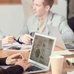 AI-Native Operator: Para profesional sedang bekerja dan berdiskusi menggunakan laptop