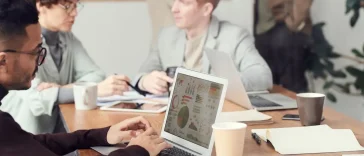AI-Native Operator: Para profesional sedang bekerja dan berdiskusi menggunakan laptop