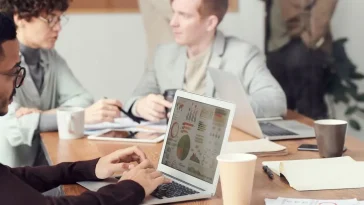 AI-Native Operator: Para profesional sedang bekerja dan berdiskusi menggunakan laptop