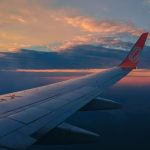 Berburu tiket pesawat murah: Ilustrasi pesawat terbang di langit cerah di atas awan