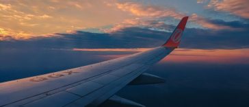 Berburu tiket pesawat murah: Ilustrasi pesawat terbang di langit cerah di atas awan