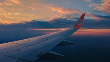 Berburu tiket pesawat murah: Ilustrasi pesawat terbang di langit cerah di atas awan