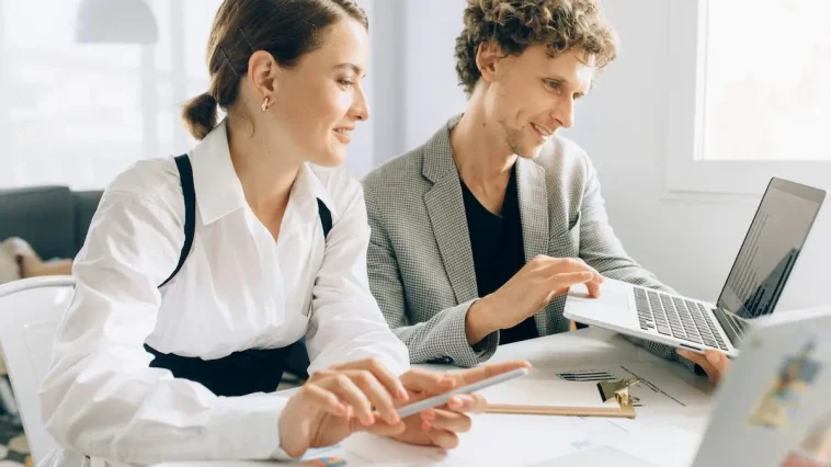 Ilustrasi dua profesional saling tersenyum dan menjaga relasi profesional di ruang istirahat kantor