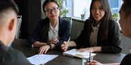 Ilustrasi profesional menerapkan teknik negosiasi kompromi dalam diskusi antar-divisi di kantor