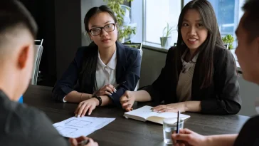 Ilustrasi profesional menerapkan teknik negosiasi kompromi dalam diskusi antar-divisi di kantor